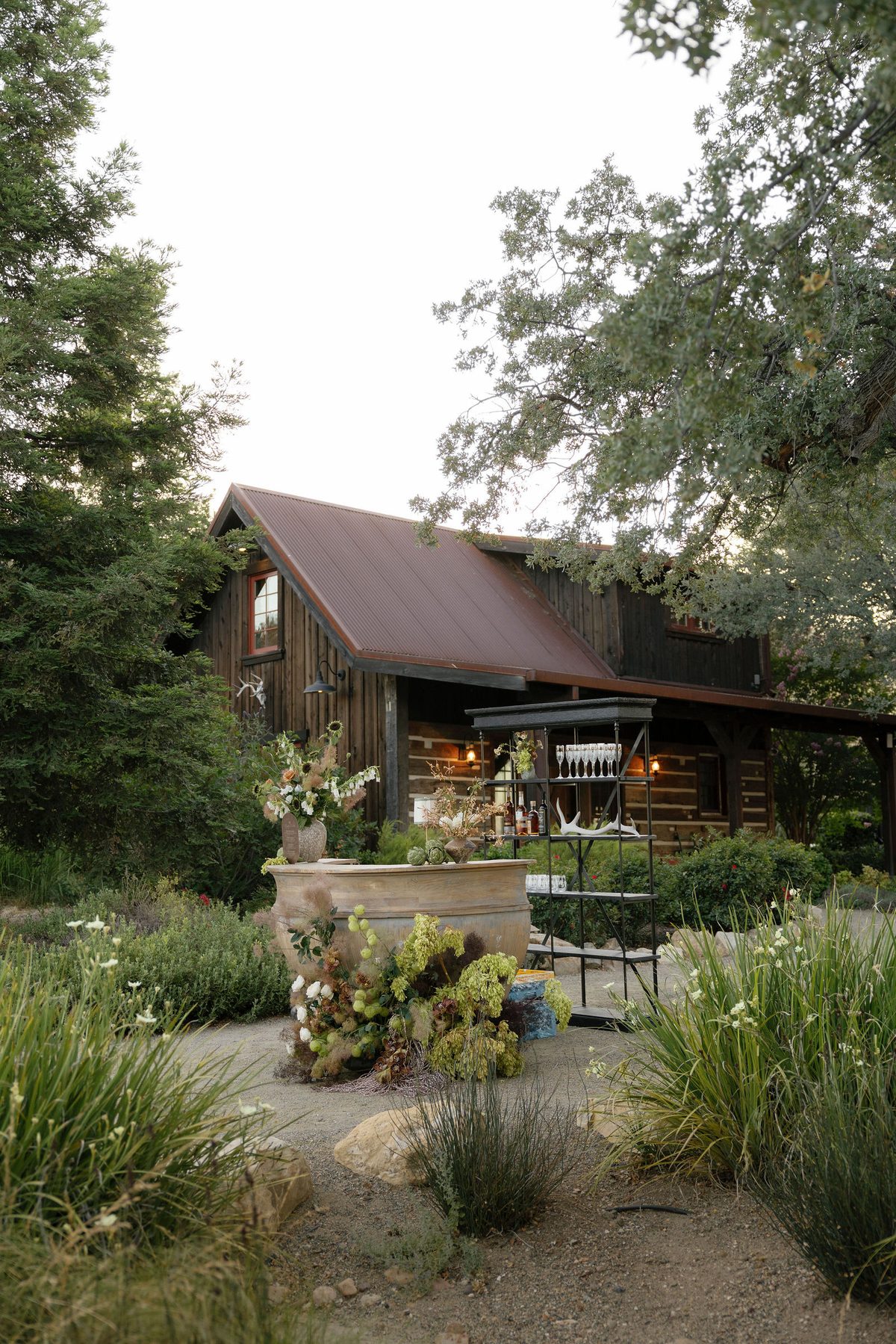 A bar set in a stone urn beneath the oaks, the lodge behind