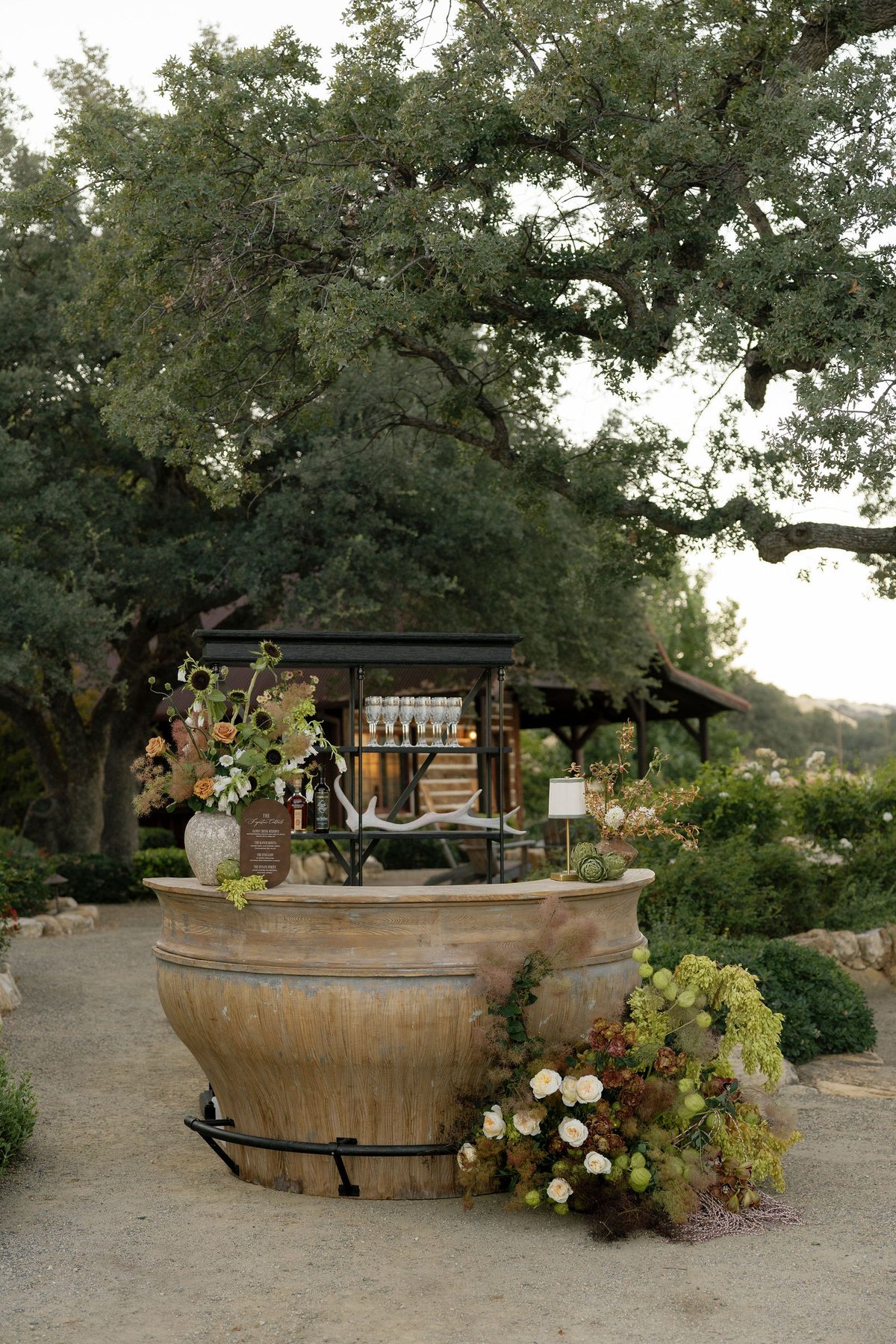 A stone-urn bar with florals under the oaks